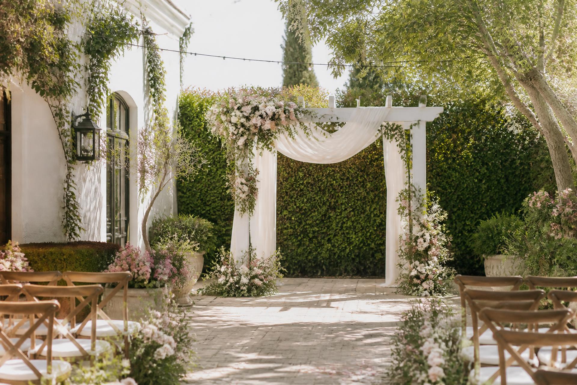 The ceremony garden at Tina's Garden with hedges, string lights, and a floral arch